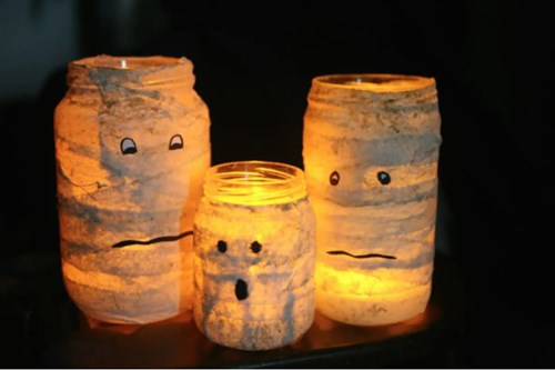 Eco friendly decorations- Reusable jars wrapped in toilet paper with spooky faces, with tea light.